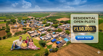 Family of four sits on a grassy hill overlooking a rural village with open fields and a large ad banner advertising residential plots ₹1,50,000 and a 'Book Now' button